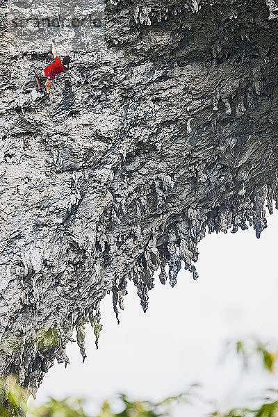 Mann klettert auf den natürlichen Felsbogen auf dem Mondberg in Yangshuo