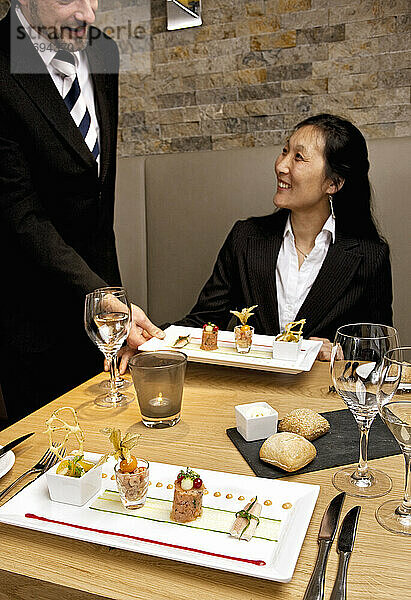 Kellner überreicht Vorspeise an Geschäftsfrau in Luxusrestaurant