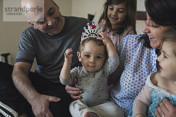 Glückliche Familie mit Mama  Papa  2 Mädchen und einem Baby  das eine Krone trägt