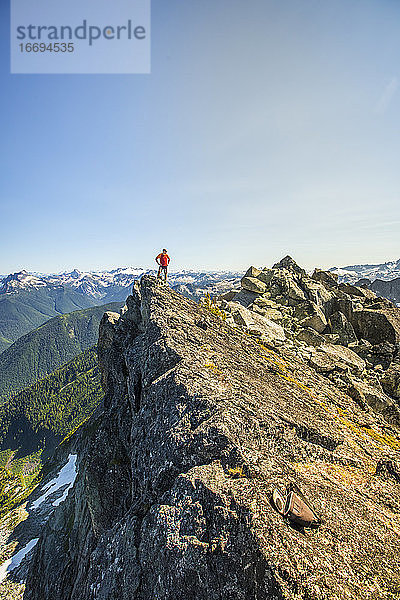 Bergsteiger steht auf dem Gipfel eines felsigen Berges  B.C. Kanada