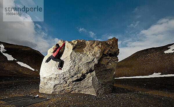 Frau beim Bouldern am Felsen im ländlichen Island