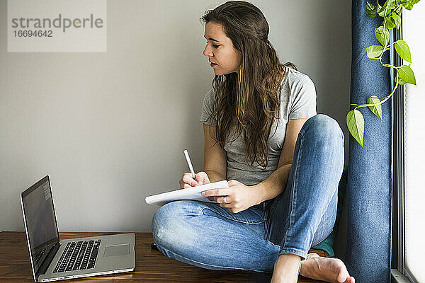 Einzelne Frau an ihrem Laptop bei der Arbeit / beim Lernen zu Hause