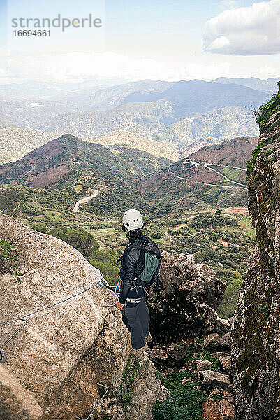Konzept: Abenteuer. Bergsteiger Mann mit Helm und Gurtzeug. Blick von hinten auf die andalusische Naturlandschaft. Klettern auf den Gipfel des Berges. Via ferrata auf Felsen.