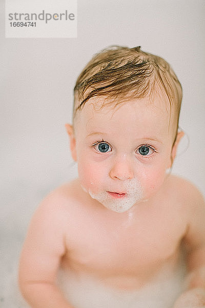 Nahaufnahme eines Babys in der Badewanne mit Blasen im Gesicht