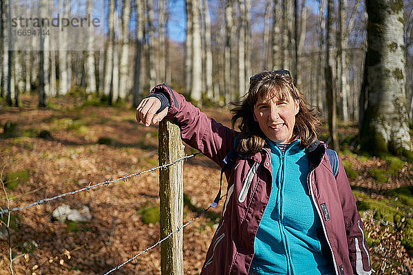 Porträt einer behüteten Frau  die im Herbst durch einen Wald spaziert