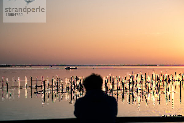 Mann beobachtet den Sonnenuntergang in der Albufera von Valencia im Gegenlicht