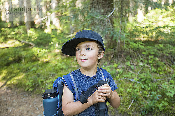 Porträt eines jungen männlichen Wanderers mit Rucksack im Wald.