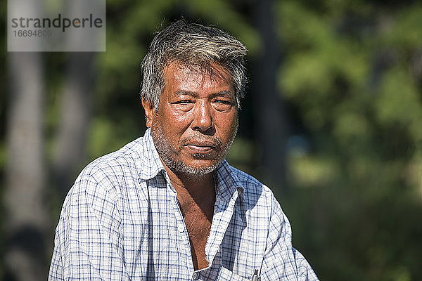 Älterer burmesischer Mann sucht sitzend im Freien  Inwa  Mandalay  Myanmar