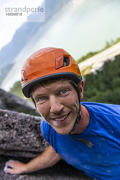 Porträt eines gut aussehenden Kletterers mit Helm in einer Mehrseillängenroute