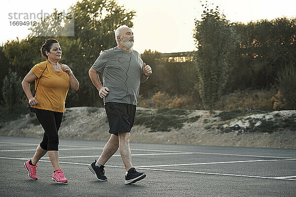 Eine Frau und ein älterer Mann joggen auf der Straße