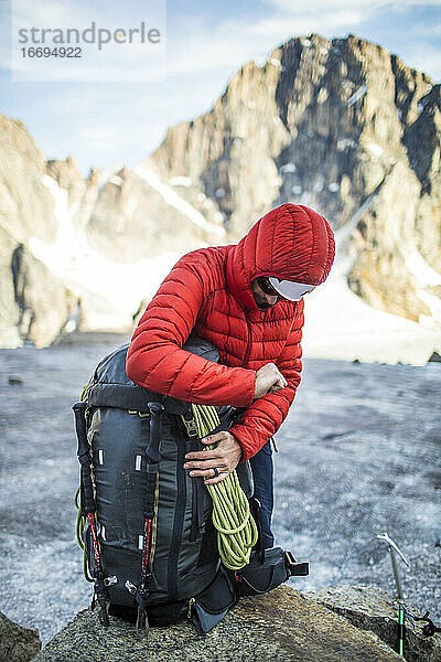 Bergsteiger packt seinen Rucksack in einer Berglandschaft.