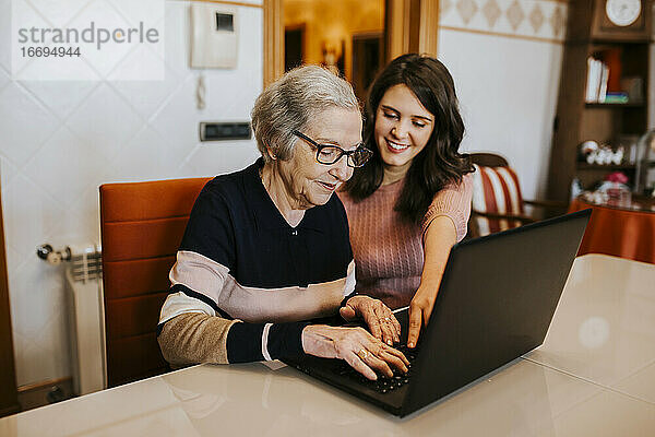 Enkelin bringt ihrer Großmutter etwas auf dem Laptop bei