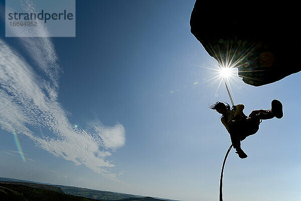 Frau beim Abseilen von einer Klippe bei den Windgather-Felsen im Peak District