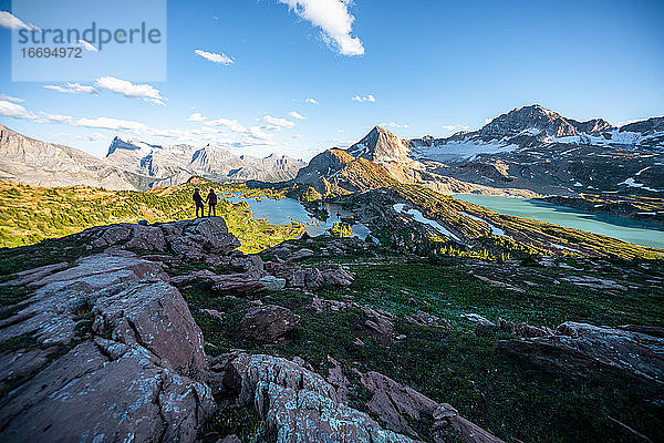 Paar hält Hände während des Sonnenuntergangs umgeben von Bergen in den Rockies