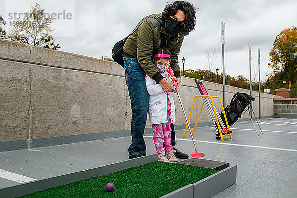 Vater und Tochter spielen Minigolf im Halloweenkostüm