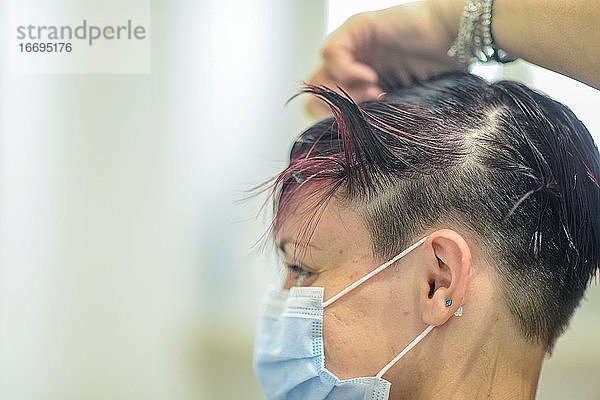 Junge Frau trägt eine Gesichtsmaske in einem Schönheitssalon und schneidet ein Styling