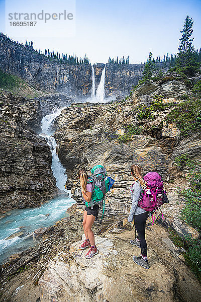 Zwei Wanderer bewundern den Wasserfall Twin Falls im Yoho National Park