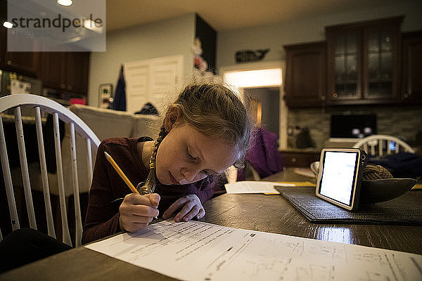 Close-in View of Young Girl At Kitchen Table Doing School Work