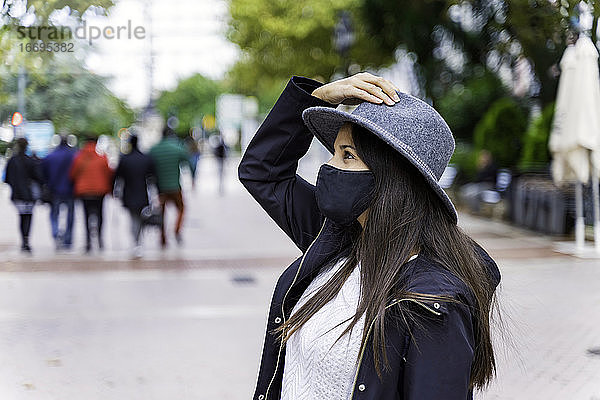 Junge Frau mit Gesichtsmaske und Smartphone in einer Stadt