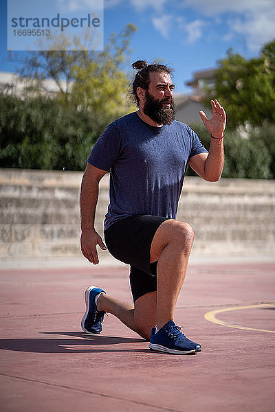 Mann trainiert seine Beine mit Power-Lunges in einem Park im Freien