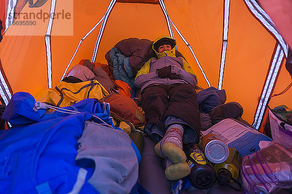 Junge Wanderin in warmer Kleidung beim Ausruhen im Zelt