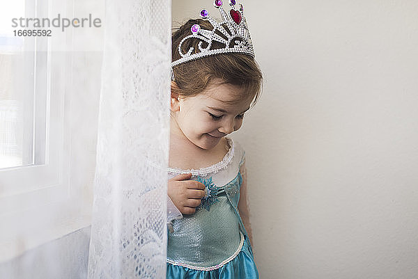 Lächelndes 4 Jahre altes Mädchen in blauem Prinzessinnenkleid und Krone gekleidet
