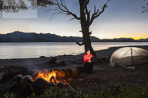 Frau arbeitet am Laptop in einem Camp am Nahuel Huapi See in Patagonien