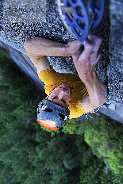 Mann platziert große Nocken in einem nicht ganz so breiten Granitriss beim Klettern in Squamish