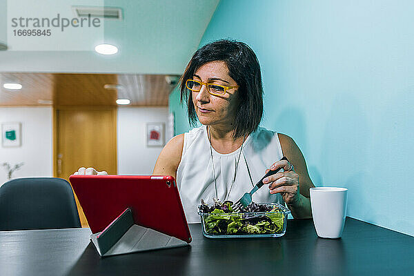 Eine Frau benutzt eine Tablette  während sie sich gesund ernährt