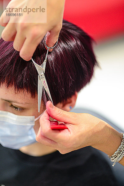 Junge Kundin in einem Friseursalon mit Gesichtsmaske