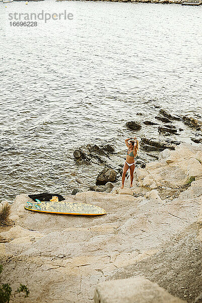 Junge Surferin im Bikini an der kleinen Bucht in Moraira