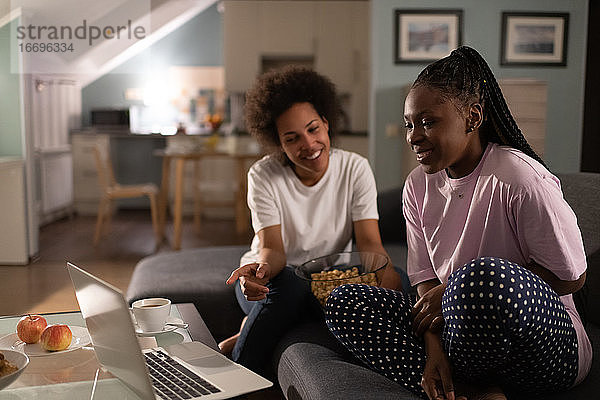 Fröhliche multiethnische Frauen diskutieren über einen Film  während sie auf ihren Laptop schauen