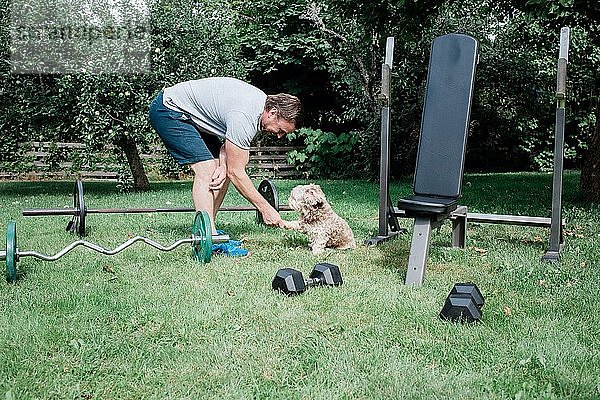 Mann hält die Pfote seines Hundes  während er zu Hause in der Quarantäne trainiert