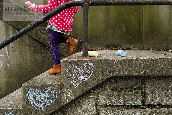 Mädchen malt mit Kreide auf einer Treppe