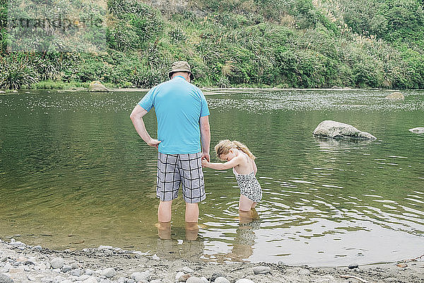 Vater und Tochter an einem malerischen Fluss  die im Wasser spielen