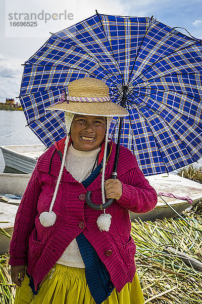 Porträt einer lächelnden Frau in traditioneller Kleidung mit Regenschirm  Uros-Inseln  Titicacasee  Peru