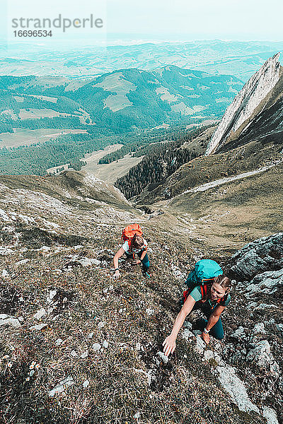 Frontalaufnahme von Frauen  die einen steilen Felsen in den Schweizer Alpen besteigen