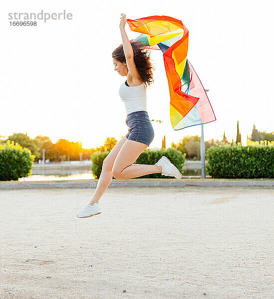 Junge Frau springt mit einer lgbt-Flagge