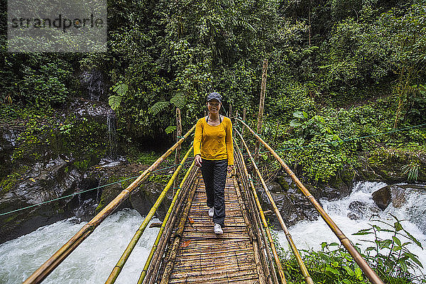 Frau beim Wandern über eine Bambusbrücke im Regenwald in Mindo  Ecuador