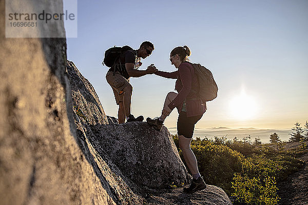 Zwei Wanderer helfen sich auf dem Appalachian Trail in Maine gegenseitig den Berg hinauf