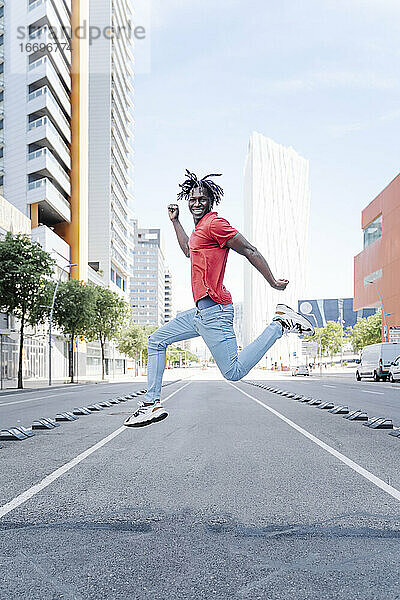 Aufgeregter ethnischer Mann springt auf der Straße