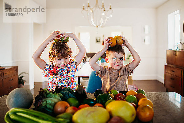 Junge und Mädchen sitzen am Küchentisch und spielen mit Obst