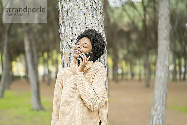 Afrikanische Frau mit Afro-Haar  die mit ihrem Smartphone spricht