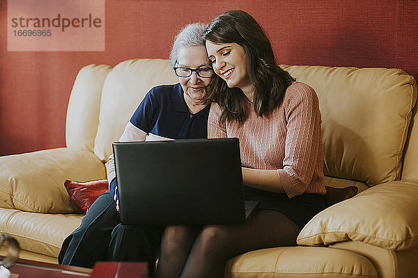 Enkelin zeigt ihrer Großmutter etwas auf dem Laptop