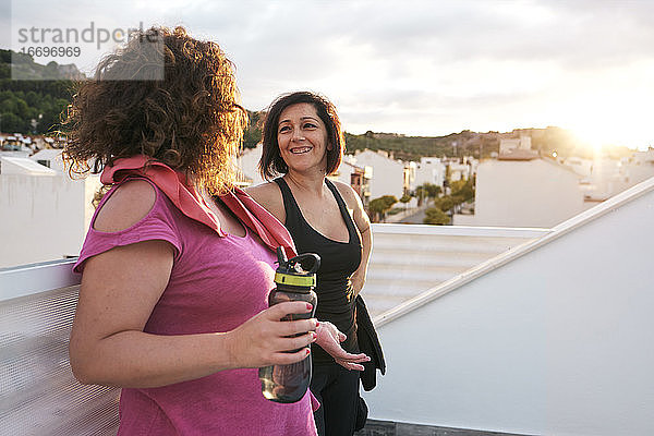 Frauen im Gespräch  während sie sich vom Sport ausruhen  mit einem Sonnenuntergang im Hintergrund