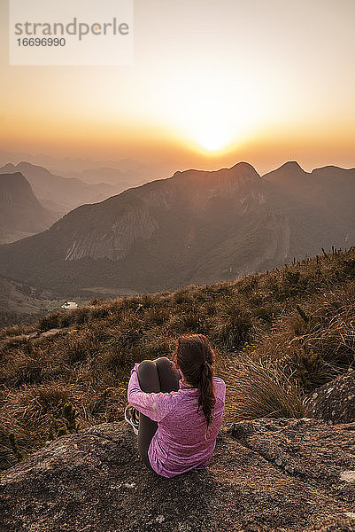 Schöne Aussicht auf eine wandernde Frau  die den Sonnenuntergang vom Berggipfel aus genießt