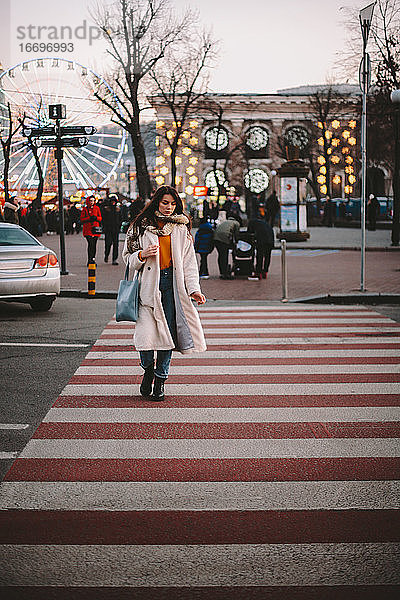 Nachdenkliche junge Frau beim Überqueren der Straße in der Stadt im Winter