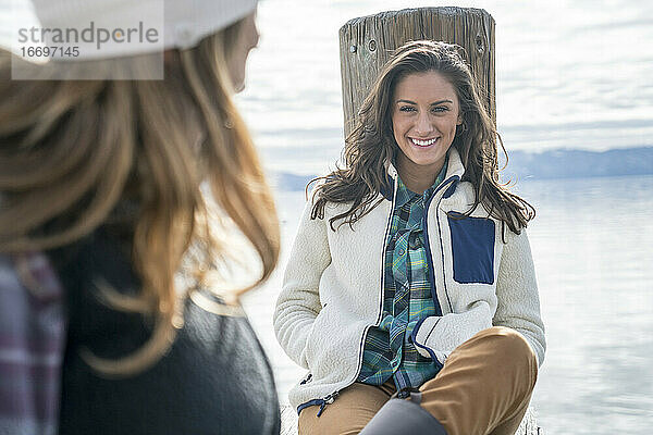 Lächelnde Frau  die mit ihrer Freundin am Pier abhängt