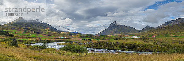 Panoramaaufnahme von Bauernhöfen und Bergen gegen bewölkten Himmel  Nordisland  Island  Europa