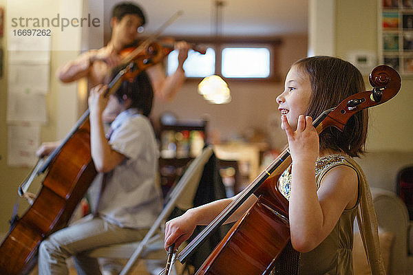 Ein glückliches Kind spielt Cello mit seiner Familie im Hintergrund  die Musik spielt